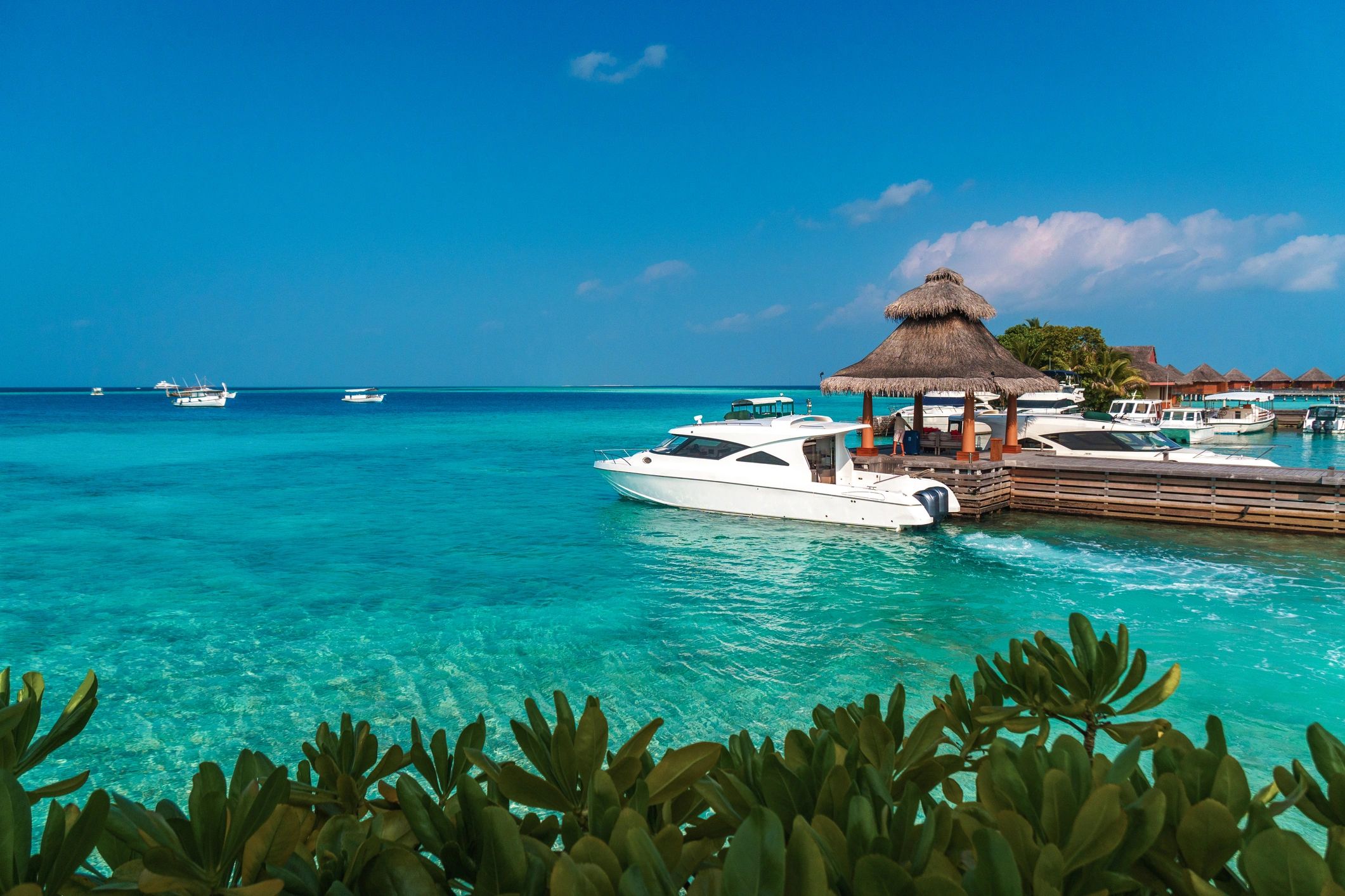 Tropical Maldives island background. Pier with yachts and turquoise lagoon waters and blue sky on a bright summer day.
