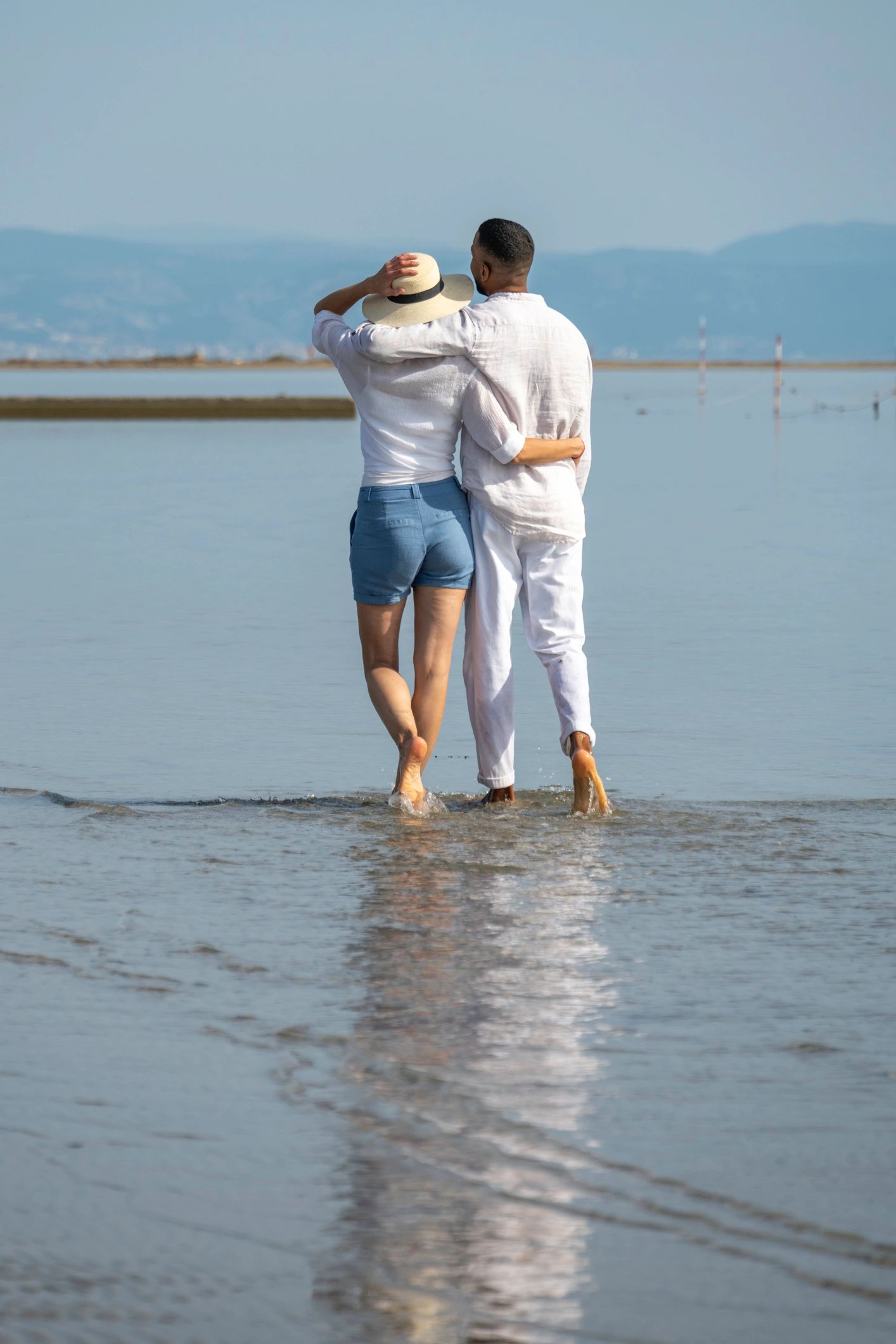Couple walking along coastline back view
