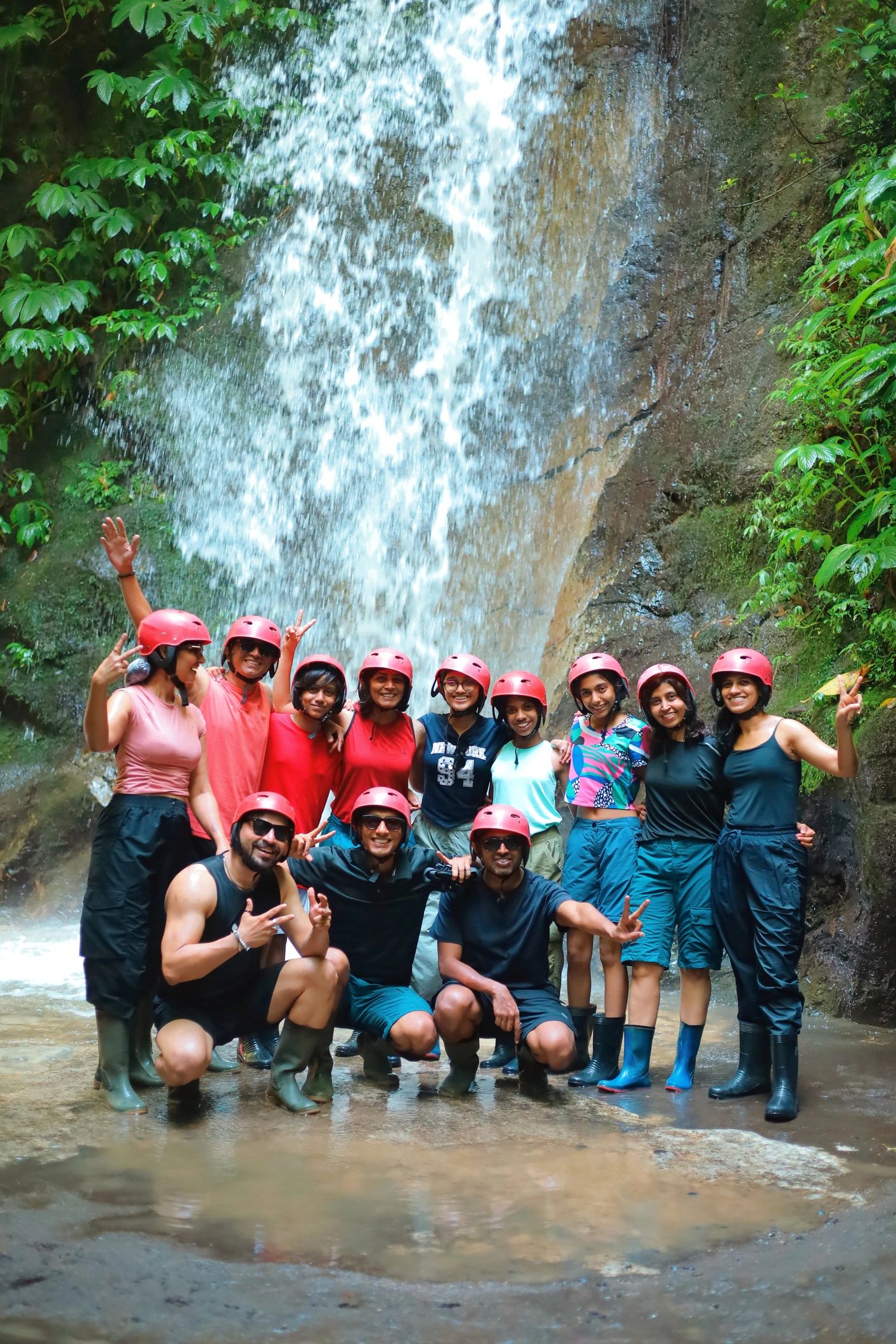 Group of friends standing in front of a tropical waterfall after an ATV adventure